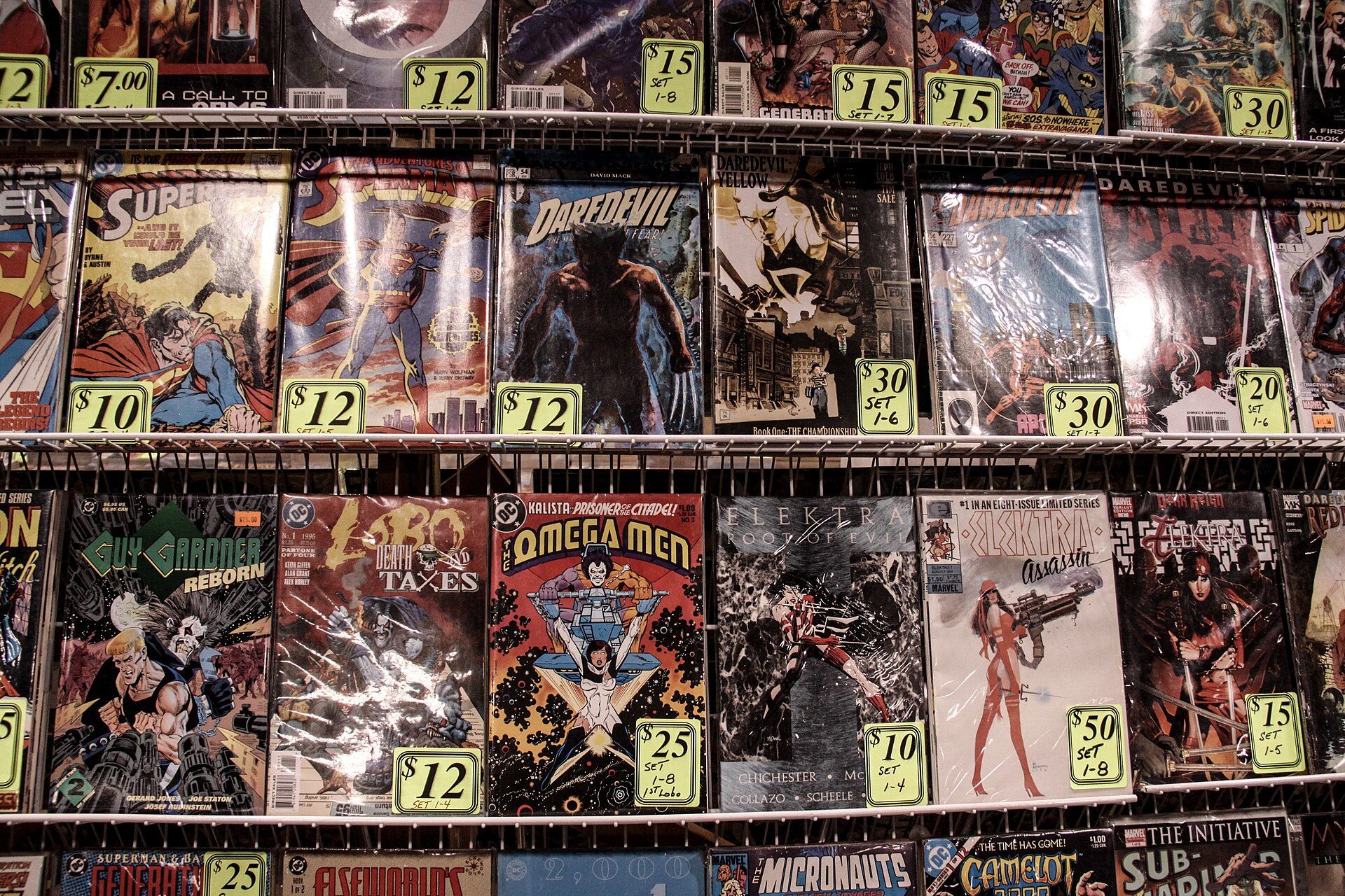 A shelf of vintage and modern comic books, including superhero titles, are displayed with price tags for sale at a fandom.