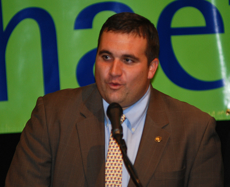 A man speaks into a microphone at a fandom event, highlighting the community aspect of fan culture.